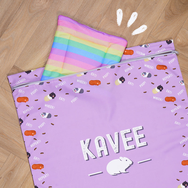 Kavee purple laundry bag on wooden floor with fleece accessory and illustration
